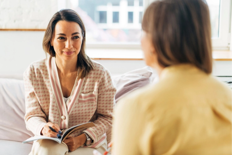 Two women sitting down together and conversing.