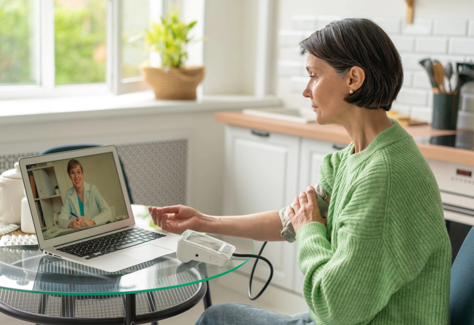 A woman sitting at a desk and taking her blood pressure.