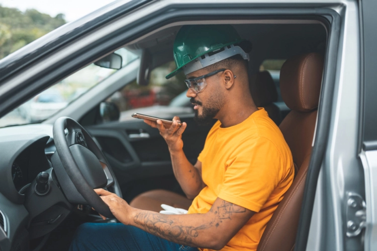A construction worker sitting in their car and speaking on the phone.
