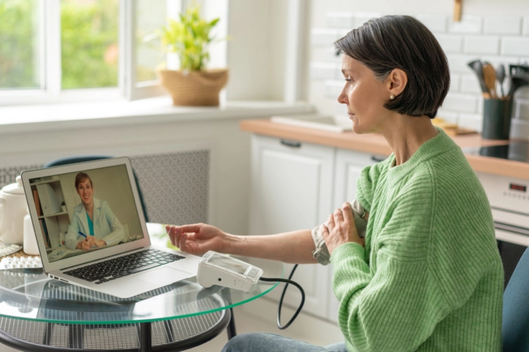 A woman sitting at a desk and taking her blood pressure.